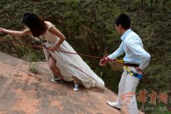 传奇开区一条龙转载：组图：情侣悬崖上拍婚纱照 男方腰上被勒出